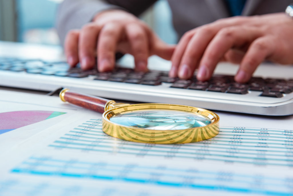 Finance professional working on keyboard with reports