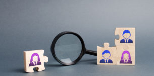 Unsorted team puzzle and magnifying glass. Search, recruitment staff, hiring leader. Lack of specialists in the labor market. Creating an efficient and productive business unit